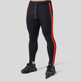 Fitness pants for men made of polyester, featuring a slim fit design with red side stripes. Ideal for workouts, available in sizes M-XXXL.