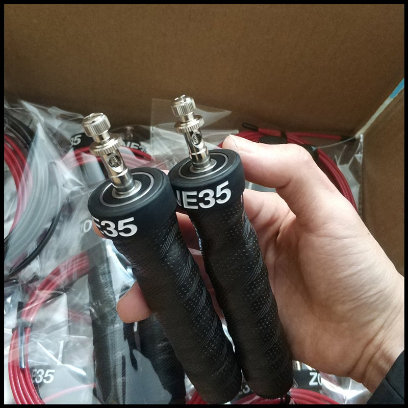 Hand holding a pair of black jump rope handles with metal connectors. Designed for high-speed skipping and endurance training.