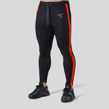 Black fitness pants for men with red side stripes, made from polyester for workout and exercise. Available in sizes M-XXXL.