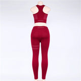 Back view of red yoga set on a mannequin, showcasing perforated details. High-waisted leggings and racerback top for a secure fit.