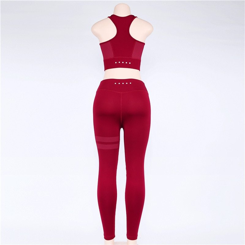 Back view of red yoga set on a mannequin, showcasing perforated details. High-waisted leggings and racerback top for a secure fit.