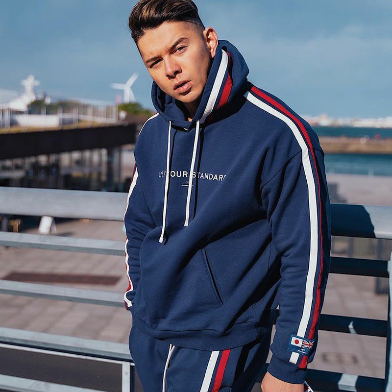 Navy blue sports fitness pullover with red and white striped sleeves, worn outdoors by a model. Cotton hoodie available in sizes S-3XL.