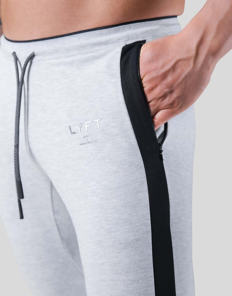 Men's light gray fitness pants with black side stripe and drawstring waist. Made from polyester, ideal for workouts and available in multiple sizes.